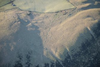 Oblique aerial view of the township, field system, hut circles, ring cairns and cairnfield on Strone Hill, looking SW.