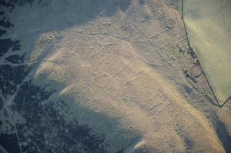 Oblique aerial view of the township, field system, hut circles, ring cairns and cairnfield on Strone Hill, looking SE.