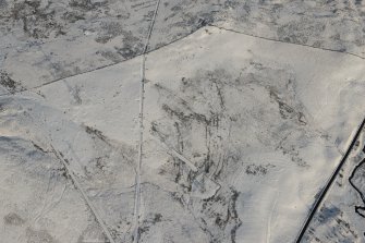 Oblique aerial view of the building, clearance cairns and military road at Corrymuckloch, looking NNW.