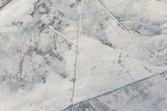 Oblique aerial view of the building, clearance cairns and military road at Corrymuckloch, looking SSW.