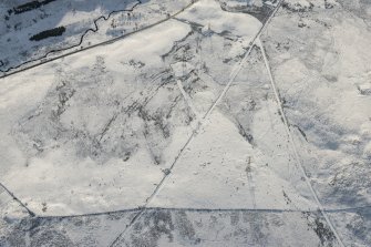 Oblique aerial view of the building, clearance cairns and military road at Corrymuckloch, looking S.