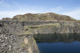 Quarry (NM71NW 118.00), north east face, view from west. Remains of quarry buildings (NM71MNW 118.02) and retaining wall, strengthening the working platform and building platform above.