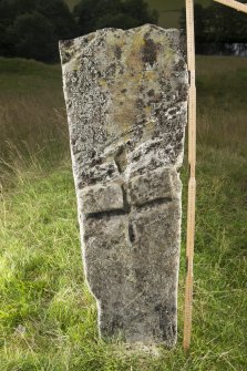 View of upright slab with incised cross in middle of stone (including scale)