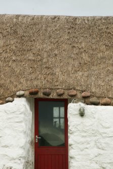 View of door showing thatching and stone weights; restored19th century thatched cottage, Tiree, Kilmoluaig.