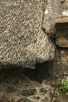 Detail of thatch and netting beside skew; St John's Cottage , 11 Bow Road, Auchtermuchty.