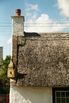 Detail of thatched roof and scobed ridge with chimney stack and sundial; Rose Cottage, Collessie.