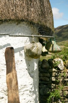 Detail of eaves on thatched roof showing metal poles and stone weights; 12 Lower Ardelve.