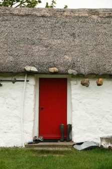 View of thatched roof, ridge and stone weights above entrance door;  2 Luib, Skye.