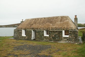 Front view of probable 19th century marram thatched cottage with stone weights; Laimrig Ruadh, Berneray.