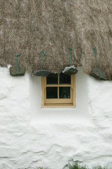 Detail of thatch and stone weights above window;  probable 18th century thatched cottage; Struan Ruadh, Malaclete.