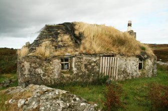 View of late 19th century cottage in advanced state of deterioration with badly overgrown thatch: 1 Aird Cumhang, Hacklet, Benbecula.