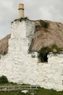 View of chimney stack and damaged thatch; 11 Rhugha Sinish, South Uist.