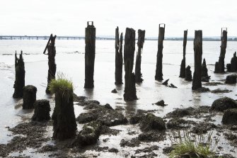 Remains of timber wharf or quay posts, view from north west. The horizontal timbers have decayed. The timber quayside deck onto which cargo and materials to be shipped in and out would have been stored is now gone.