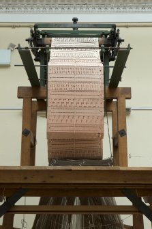 Interior. General view. Jaquard loom in gallery area. View of cut or punch cards. The holes and blanks on the cards allow the hooks in the frame to select or not select threads to create the complex patterns in the cloth

