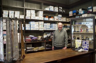 Portrait of Mr Alexander Hunter at his shop counter.