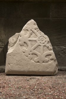 Obliquely lit view of medieval cross slab fragment.
