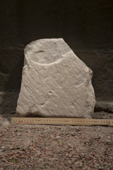 Obliquely lit view of medieval cross slab fragment (with scale).