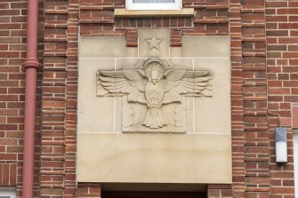 South front. Detail of carved plaque above presbytery door.