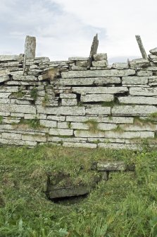 W wall of E building, view showing exposed drain beneath wall, running W to possible well