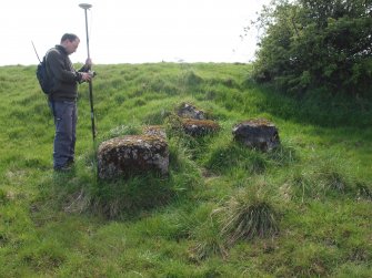 Allan Kilpatrick surveying a cluster of concrete blocks at the foot of the scarp