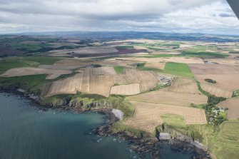 General oblique aerial view of the Aberdeenshire landscape centred on Kinneff Parish Church.