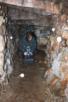 Archaeologist Gemma Hudson preparing equipment for the laser scan survey inside Cracknie souterrain, Tongue