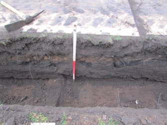 North facing section showing layer of rubble spread seperating topsoil from subsoil at western end of trench. 1.00m scale, direction S