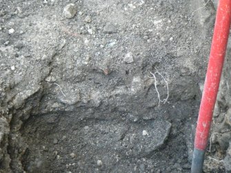 Trench 2. Section at E end of slot showing deposit (012), band of mortar (013) and (014) brown soil with rubble below floor horizon (011), direction E