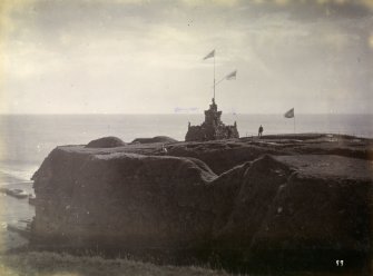 Photograph of Mervyn Tower at Nybster Broch on second promontory, shown with flags.