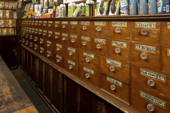 Coldstream, 81 High Street. Interior. Detail of bank of drawers with their glass painted and gilded labels and glass handles.