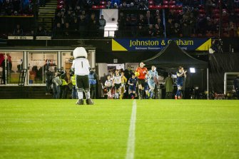 Detail of football teams emerging from the players tunnel to pitch with mascot, taken from the north west. Under floodlights.