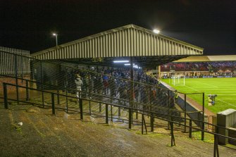 General view of the east covered terracing with the 'home' fans taken from the north west. Under floodlights.