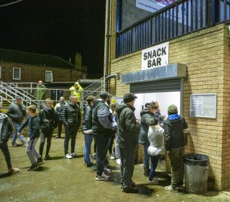 General view of snack bar at east end of main stand taken from the north west. Under floodlights.