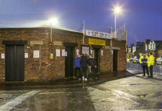 General view of south east turnstile area with approaching fans, taken from the south. Under floodlights.