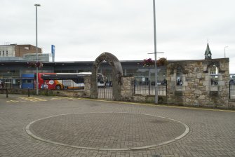 View from north showing remains of wall outside Gillespie Centre, Chapel Street, Dunfermline, with Dunfermline Bus Station visible behind
