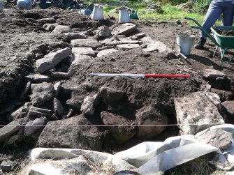 Outer wall, in situ wall-facing stones and collapsed wall-fill, to left, rubble fill of intramural passage