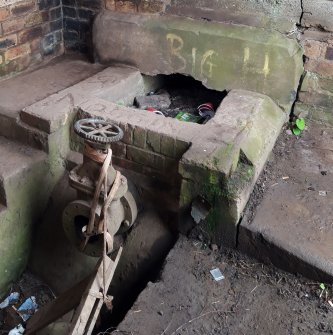 View of WSW end of channel in the floor of the pump-house, showing pipe valve.