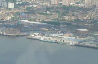 Low angle aerial view of part of Dundee waterfront backed by the historic Cowgate Port (aka East Port) area of the city, looking N.
