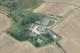An oblique aerial view of Gilchrist church burial grounds and Gilchrist farm buildings, Muir of Ord, Black Isle, looking NW.