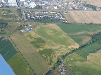 Aerial view of Lower Ardnagrask, The Cairns and Muir of Ord Industrial Estate with various cropmarks, Black Isle, looking E.