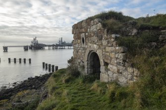 The Monk's Cave.
General view of entrance from north. Braefoot Marine Terminal and the remains of the boom defence to Inchcolm Island are also visible.