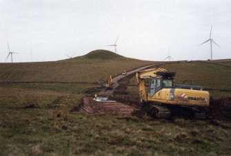 Report illustration 2: 'Road excavation showing Knock Jargon Hillfort in background', Archaeological works, Ardrossan Windfarm Extension, Ardrossan, North Ayrshire