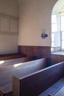 Detail of pews with fragment of earlier panelling behind.