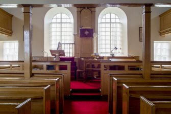 View to south showing pulpit, lectern, communion table, font, pews and gallery pillars