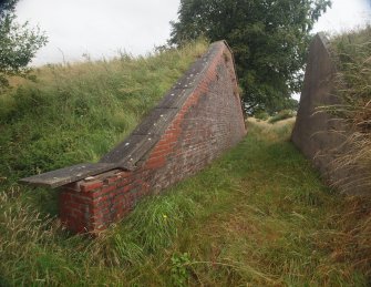 Explosives Magazine R49: the W entrance for the narrow gauge railway through the blast wall showing the restored brickwork around the crest of the S revetment and the concrete revetment opposite