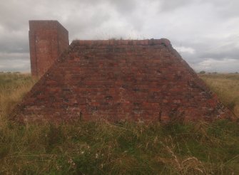 Unbuilt Explosives Magazine at Hill 1: view from the SSE of the brick revetment overlooking the narrow gauge railway line, with the brine tank tower of Nitroglycerine Hill I in the background