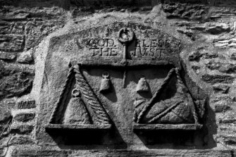 Detail of carved panel above south doorway showing weighing balance and inscribed 'God bless the just'