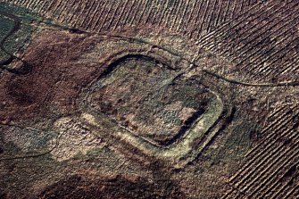 Oblique aerial view of Castle Greg Roman fortlet.  Ploughing for afforestation has encroahed right up to the earthworks.