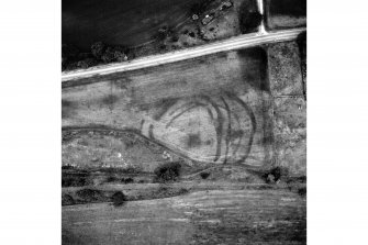 Oblique aerial view centred on the sequence of defensive ditches, revealed as cropmarks, around the fort at Wester Carmuirs. Within the fort there are traces of a roundhouse.The cropmarks of a palisaded enclosure (NS88SW 50), also containing a roundhouse, are also visible on the photograph.