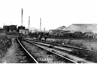 Copy of postcard showing general view of shale oil works at Oakbank, with group of children by railtracks.  Insc. "Oakbank, Oilworks".